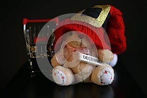 Red Christmas hat, coins in miniature of trolley and cute teddy bear toy isolated on black dark background
