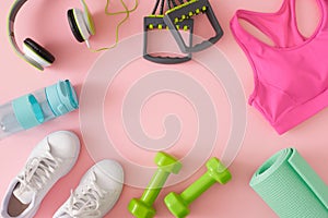 Creative layout made of sports equipment, white sneakers and sports top on pastel pink background