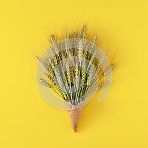 Creative layout made of wheat ears with ice cream cone on yellow background.