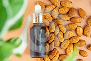 Creative layout. Natural almond oil in a matte glass bottle and scattering of almonds on a pastel beige background. The