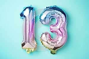 Creative layout. Rainbow foil balloon number, digit thirteen. Birthday greeting card with inscription 13. Anniversary