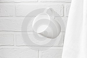 Creative levitation of a white cup against the background of a kitchen stone brick wall and milky-colored textiles, clean