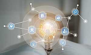 Creative light bulb concept with digital icons representing ideas, innovation, and technology against a blurred