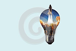 Creative light bulb with a night city, smoke and a rocket taking off. Creative idea and technology. Electricity and science,