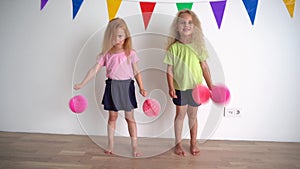 Creative little girls pretending cheerleaders holding pink pompon paper balls