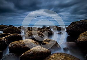 Creative longtime photo over a rock beach with fantastic Clouds on the sky