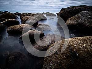 Creative longtime photo over a rock beach with fantastic Clouds on the sky