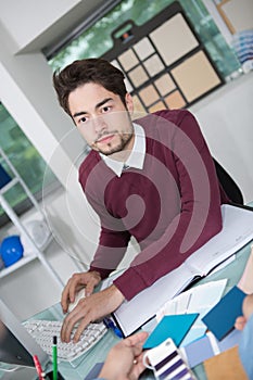 Creative male office worker with computer talking to client photo