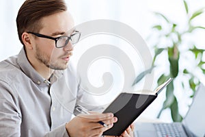Creative male worker with book at home office