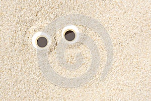 Creative minimal background for summer concept, pair of funny eyes on beach sand