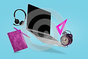 Creative minimal composition of back to school made with a laptop, headphones, school supplies and alarm clock  flying in the air