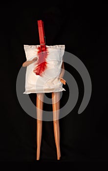 Creative minimalism period concept.Menstrual pad with hands and legs, red feather on pin on black background.Menorrhagia photo