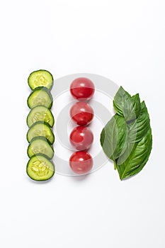 Creative mockup of tomato slices, cucumber and basil leaves. Flat lay, top view. Food concept. Vegetables isolated on a white