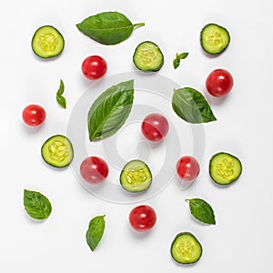 Creative mockup of tomato slices, cucumber and basil leaves. Flat lay, top view. Food concept. Vegetables isolated on a white