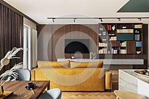 Creative and modern vintage living room interior design with yellow sofa and lamella wall with tv and bookcase. Herringbone