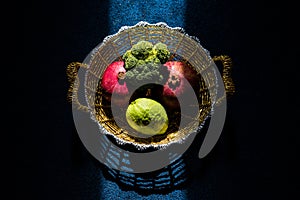 Creative moody shot of fruit and vegitable in a golden basket