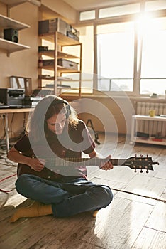 Creative musician playing guitar on floor at home