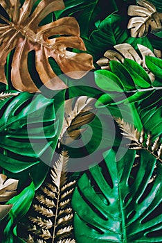 Creative nature background. Gold and green tropical Monstera and palm leaves. Minimal summer abstract jungle or forest pattern.