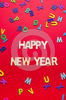 Creative New Year\'s greeting arrangement with colored letters on a red background.Holiday concept. Flat lay