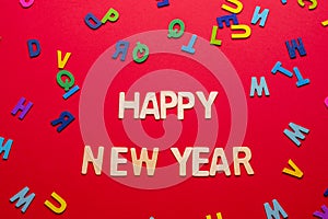 Creative New Year\'s greeting arrangement with colored letters on a red background.Holiday concept. Flat lay