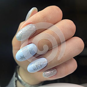 Creative New Year`s manicure. Snow manicure on colored nail Polish with silver snowflakes