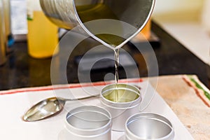 Creative occupation of candle making showing the pouring of liquid wax into jars