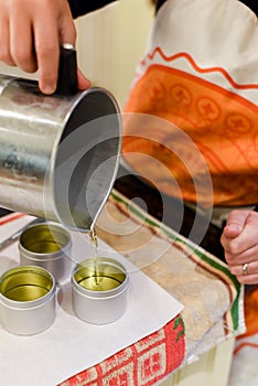 Creative occupation of candle making showing the pouring of liquid wax into jars