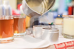 Creative occupation of candle making showing the pouring of liquid wax into jars