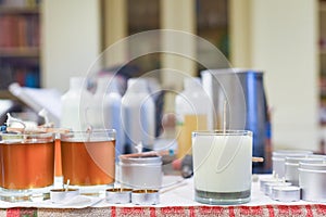 Creative occupation of candle making showing the pouring of liquid wax into jars