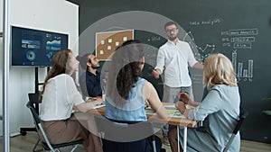 Creative office worker riding scooter in workplace doing high-five with colleagues and clapping hands celebrating good