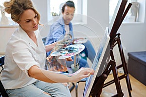 Creative painter and her protege working in a studio photo