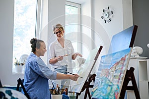 Creative painter and her protege working in a studio photo