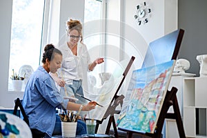 Creative painter and her protege working in a studio photo
