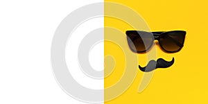 Creative party decoration concept. Black mustache, sunglasses, props for photo booths, carnival parties on yellow background top