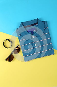 Creative party decoration concept. Black Sunglasses  polo shirt props for parties on color background top view flat lay copy space