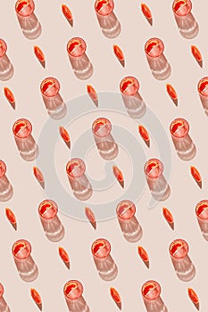 Creative pattern made of glass of fresh lemonade, water or cocktail and slice of red blood orange on pastel beige backgound with