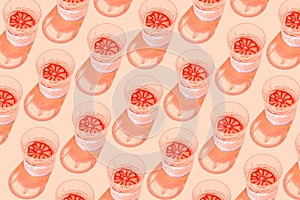 Creative pattern made with glass with lemonade or water and sliced citrus on pastel background. Summer fruit and refreshment