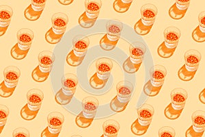 Creative pattern made with glass with lemonade or water and sliced citrus on yellow background. Summer fruit and refreshment