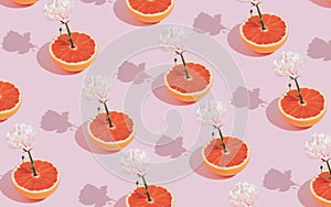 Creative pattern made of pink flower growing out of red grapefruit on pastel background. Minimal, trendy spring romance