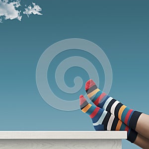 Creative person with multicolor sock relaxing with feet up