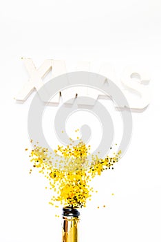 Creative photo of champagne bottle with confetti on white  background with a giant xmas decoration on top, . Flat lay of christmas