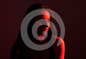 Creative portrait of a beautiful female model close-up. Red lighting in the Studio.