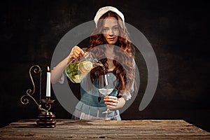 Creative portrait of young beautiful redhead girl with long curly hair in image of medieval person in renaissance style