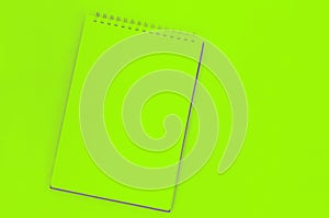 blank sheet of spiral notebook, cup of coffee on a green background photo