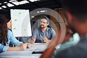 The creative process. Shot of a mature manager talking to his team while sitting around a table in an office.