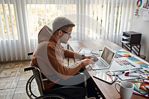 Creative professional. Side view of young male UX UI designer in a wheelchair designing new mobile app, working on