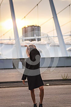 Creative redhead woman in black dress in the city on sunset