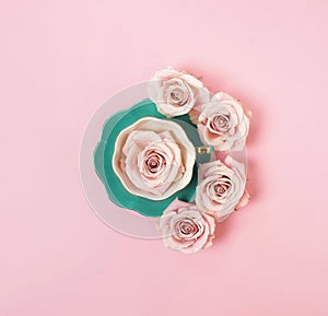 Creative romantic layout gift made of green coffee cup with pink roses on pink background.