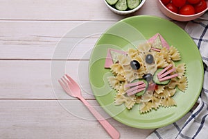 Creative serving for kids. Plate with cute cat made of tasty pasta, vegetables and sausage on white wooden table, flat lay. Space