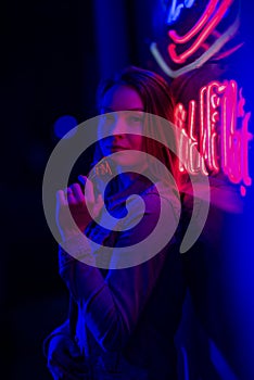 Creative sexual portrait of a girl in neon lighting with glasses, night party, dancing, game business, striptease